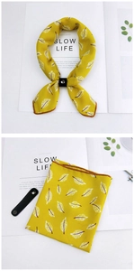 Detail of yellow silk scarf with feather prints and a black leather clasp buckle