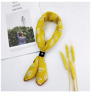 Detailed close-up of yellow cotton linen scarf with white feather print and leather ring