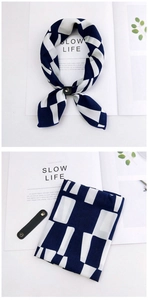Detail of navy and white geometric scarf with a black leather clasp on a magazine