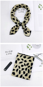 Detail of light beige floral scarf with black leather buckle strap accessory