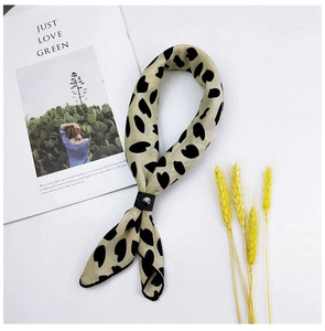 Close-up of animal print silk scarf in beige with black spots and a leather ring buckle