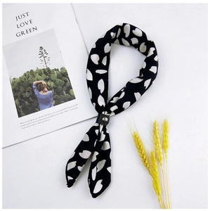 Close-up of black silk scarf with white dots and a black leather ring on white background