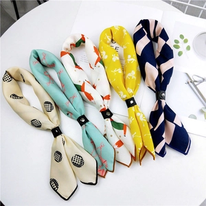Five assorted pattern silk scarves with black buckles on minimalist magazine background