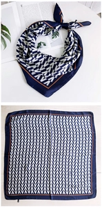 Détail d'un foulard en soie bleu marine à motifs géométriques et bordure orange