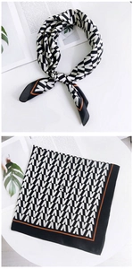 Détail d'un foulard carré en soie avec motif géométrique noir et blanc et texte VAVAV