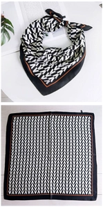 Détail d'un foulard carré avec motif VAVA, bordure orange et texture soyeuse