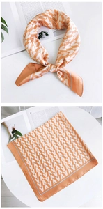Détail d'un foulard en soie orange et blanc aux motifs de lettres géométriques