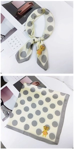 Detailed view of beige polka dot silk scarf with yellow cartoon bear motif and grey edges