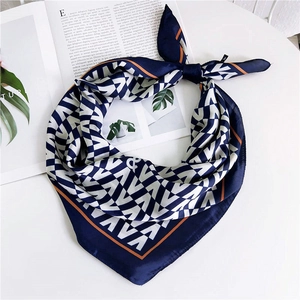 Élégant foulard carré en soie géométrique bleu marine et orange sur un bureau blanc