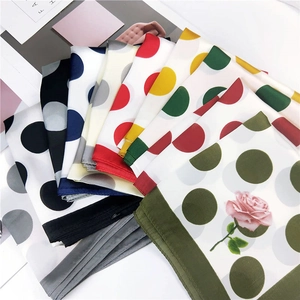 Elegant polka dot neck scarves in multiple colors displayed on a minimalist white table