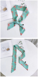 Détail macro du foulard étroit vert menthe avec motifs géométriques de flamants roses