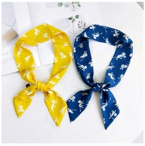 Détail de foulards en soie jaune et bleu avec imprimés singe noués sur un magazine