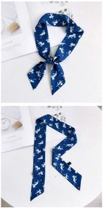 Détail d'un foulard étroit bleu foncé avec motif de singe noué sur un sac