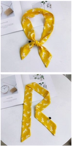 Détail d'un foulard en soie jaune avec motifs de singes blancs et finition étiquette latérale