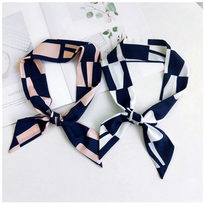 Détail de foulards en soie aux motifs géométriques bleu marine, pêche et blanc crème