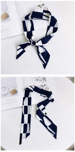Détail d'un foulard en soie étroit à motif géométrique bleu marine et blanc noué en nœud