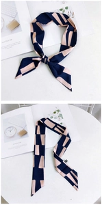 Détail d'un foulard en soie à motif géométrique bleu marine et rose poudré