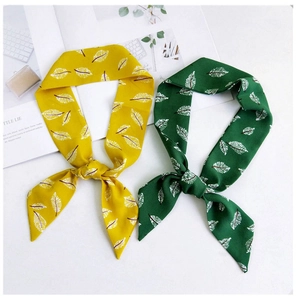 Détail de foulards à motifs de feuilles jaune et vert pour décorer les sacs à main