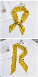 Détail d'un foulard en soie jaune avec motif de feuilles blanches noué et à plat