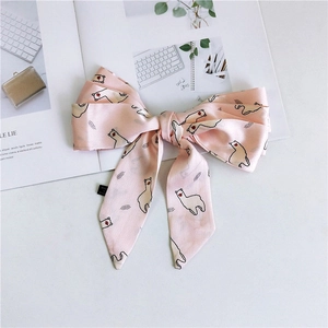 Pink satin hair bow with alpaca print on open magazine with natural lighting