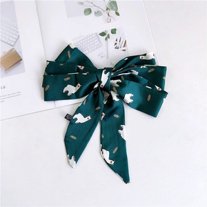 Detailed close-up of dark green satin scarf with alpaca prints and care label