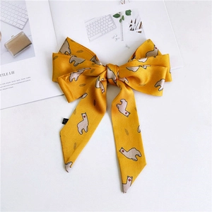 Detail of a bright yellow satin bow with cartoon alpaca prints and ribbon texture