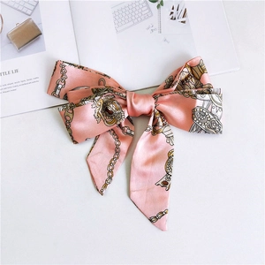 Detail of pink satin bow hair clip featuring vintage gold chain and crown pattern