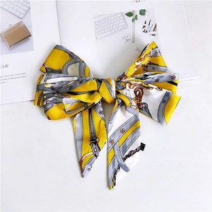 Detail of a yellow and white narrow silk scarf with equestrian horse bit print and floral pattern
