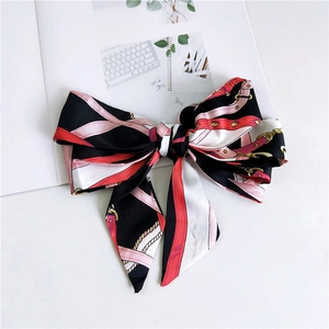 Detail view of retro printed silk ribbon with pink belt and gold chain motifs on a magazine