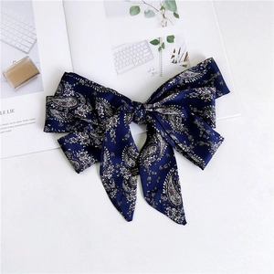 Close-up of a dark blue paisley pattern satin ribbon scarf tied in a bow with floral details