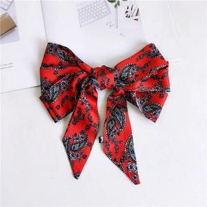 Detail of red paisley silk bow hair clip with long ribbons and side brand label