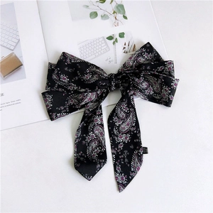 Detail of black satin hair bow with paisley floral pattern on magazine background
