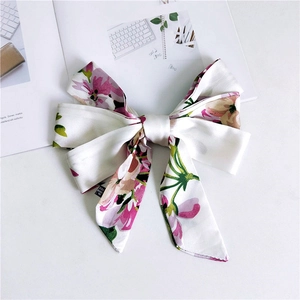 Floral print bow hair tie with long ribbons on a minimalist white fashion magazine background