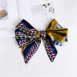 Macro detail of narrow satin scarf with geometric pattern in navy, yellow and red