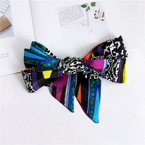 Detailed view of long narrow scarf tied in a bow with vibrant colorful geometric prints