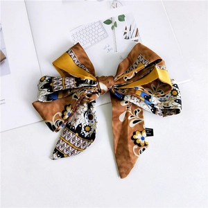 Detail of bohemian silk-like bow hair clip with floral patterns and geometric motifs