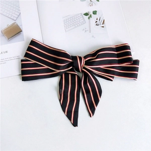 Detail of a thin black satin scarf with red and gold stripes tied as a chic bow knot