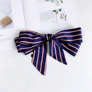 Close-up of navy blue satin striped bow scarf with ribbon tails on a white magazine