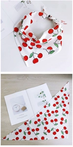 Détail d'un foulard triangulaire en soie avec imprimé cerises sur mousseline blanche