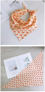 Détail d'un foulard beige en soie avec imprimé lune rouge plié et étalé à plat
