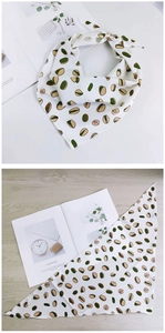 Détail d'un foulard floral avec motif pistache sur un bureau en bois et magazine blanc