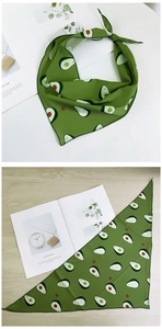 Détail d'un foulard triangle vert avec imprimé avocat sur tissu lisse et bords fins