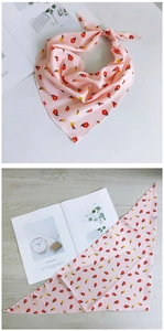 Détail macro du foulard triangle rose à fleurs montrant les ourlets fins et le tissu léger