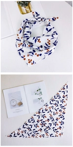 Détail d'un foulard triangle à motif floral avec feuilles bleues et baies oranges