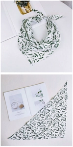 Détail d'un foulard triangulaire à fleurs avec motifs de feuilles vertes et ourlet