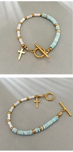 Detail of bamboo shell bead bracelet with gold cross pendant and toggle clasp closure