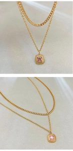 Macro detail of a double-layered gold necklace with a pink square zircon pendant