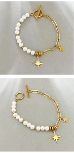 Detail of gold chain pearl bracelet featuring OT buckle and star charms on fabric