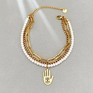 Layered gold stainless steel pearl bracelet with vintage Hamsa Hand charm on grey background