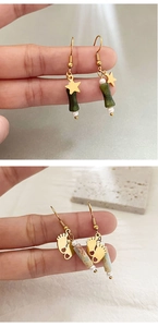 Close-up of bamboo-style gold earrings with jade-like beads and white pearls